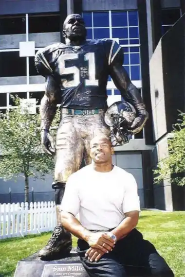Sam Mills seated in front of his No. 51 statue outside the Carolina Panthers stadium